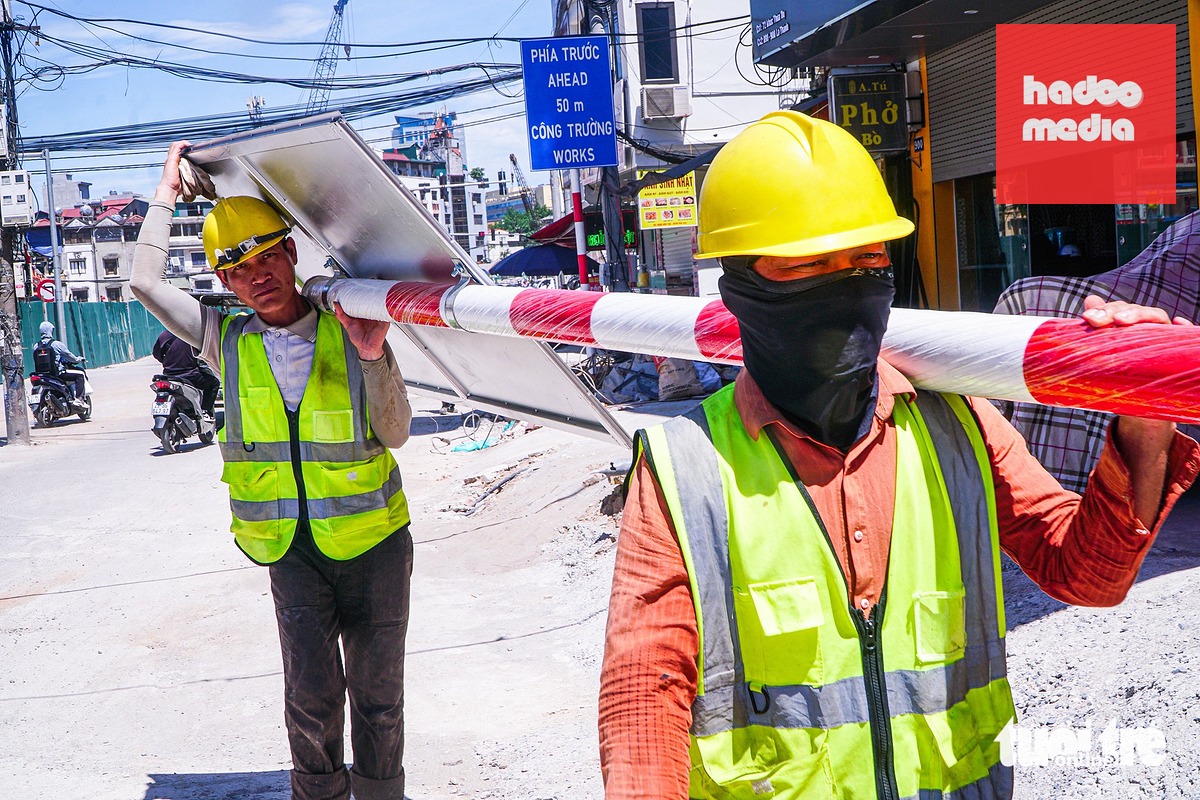 Công nhân đang lắp đặt các biển báo dọc tuyến đường Đê La Thành - Ảnh: PHẠM TUẤN