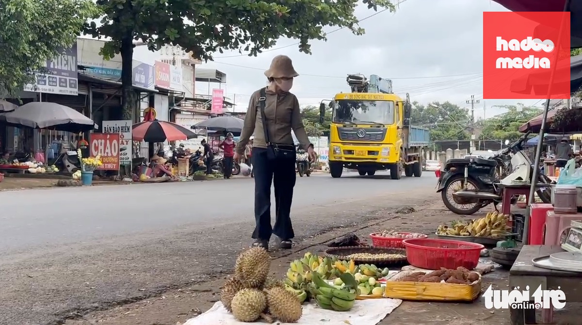 Trong khi xe tải chở cát, xe khách... lao vun vút ngay khúc cua, nhiều tiểu thương và người dân vô tư mua bán ngay lề đường quốc lộ 27 - Ảnh: MINH PHƯƠNG
