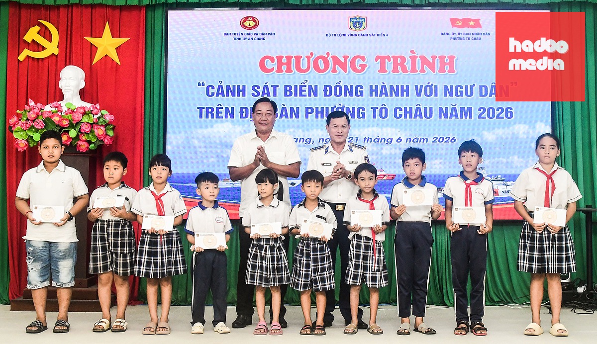 Đại tá Nguyễn Thái Dương (đứng sau, bìa phải) - Phó chính ủy Bộ Tư lệnh Vùng Cảnh sát biển 4 - trao tặng nhiều phần quà giúp học sinh nghèo ở vùng biển đảo có thêm điều kiện đến trường - Ảnh: HỒNG ĐIỆP