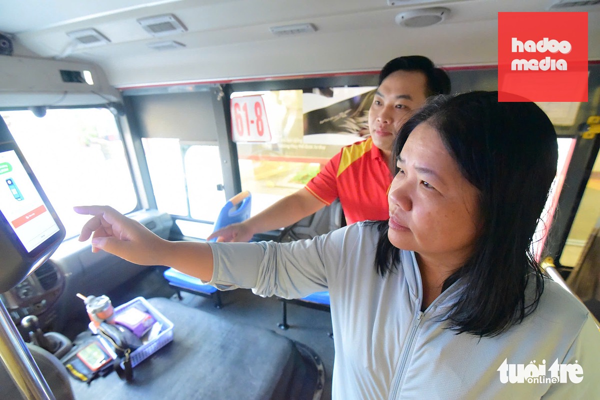 Anh Minh Tuấn, tài xế xe buýt số 61-2, hướng dẫn hành khách thao tác với máy T10 (máy xác thực thẻ và thanh toán thông minh, hỗ trợ tài xế hoặc tiếp viên thao tác nhanh chóng và in vé ngay lập tức cho hành khách) - Ảnh: TRÍ ĐỨC