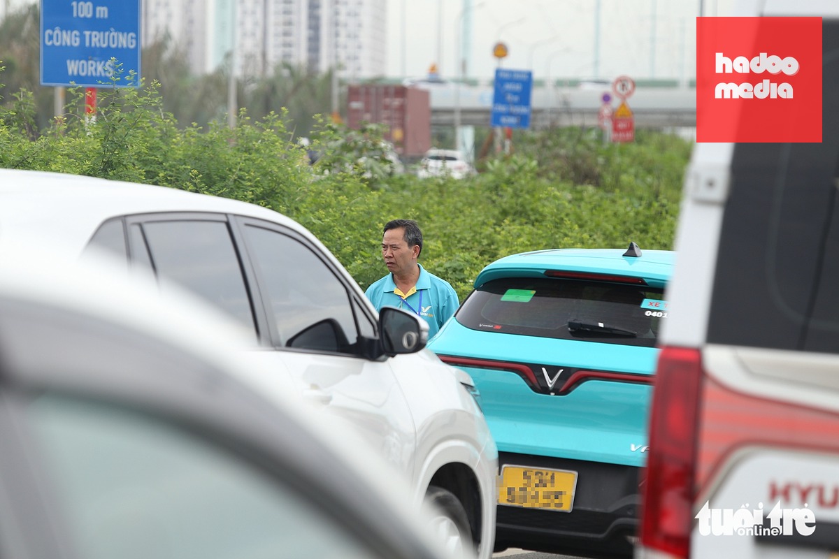 Một tài xế taxi đang chở khách đi Đồng Nai phải xuống xe hóng mát do chờ lâu - Ảnh: MINH HÒA