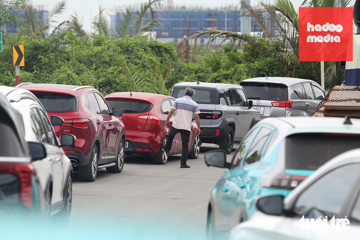 Một tài xế xuống kiểm tra xe trong lúc chờ đợi - Ảnh: MINH HÒA