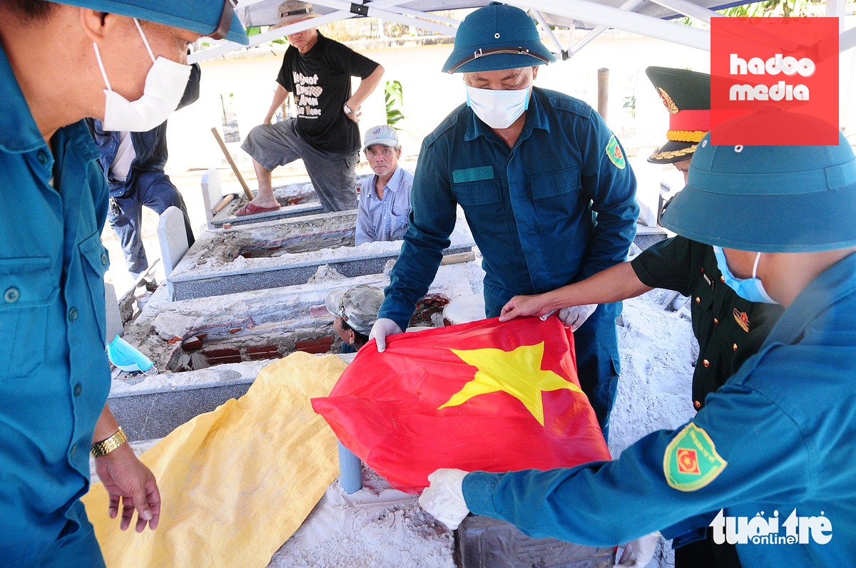 Hài cốt đưa lên khỏi mộ được bỏ vào hũ sành, phủ quân kỳ và đưa đến vị trí lấy mẫu - Ảnh: B.D.