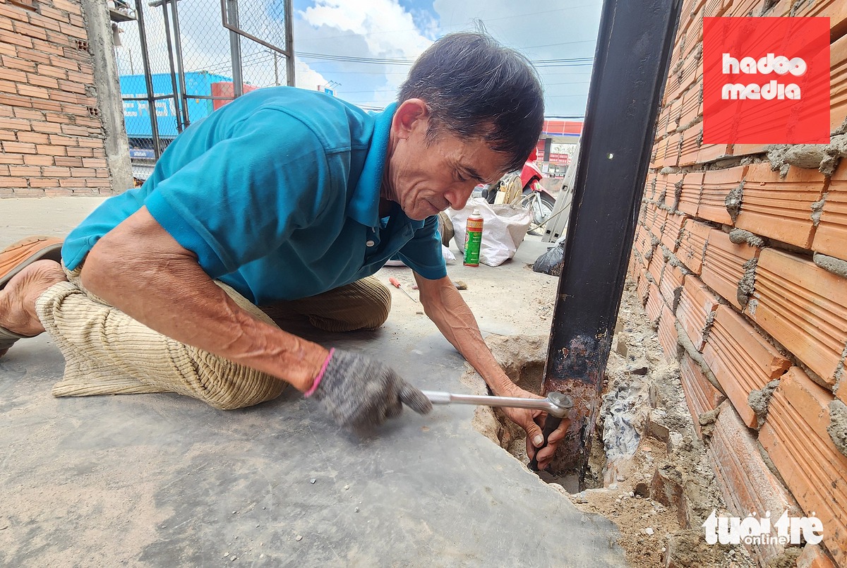 Ông Võ Văn Dũng đang tháo dỡ cây sắt trên nền nhà trống mà ông bàn giao mặt bằng cho dự án nâng cấp, mở rộng quốc lộ 1 - Ảnh: NGỌC KHẢI
