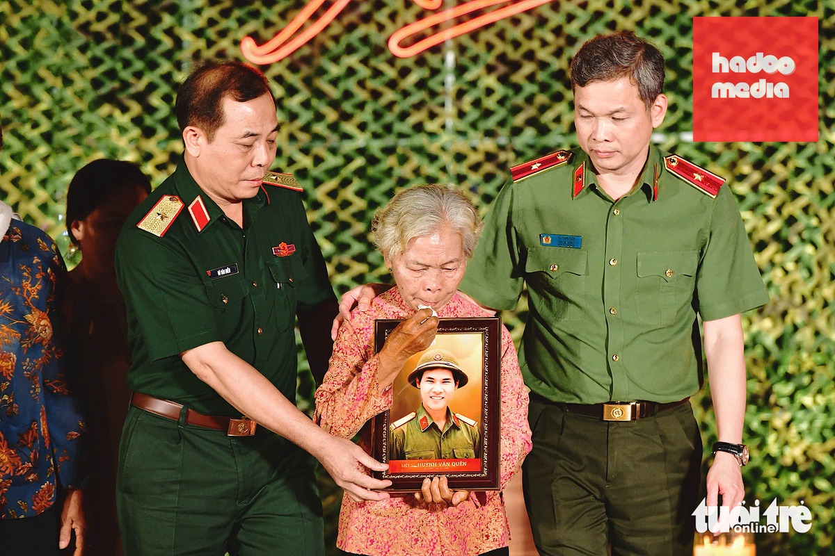 Thiếu tướng Vũ Văn Điền, Tư lệnh Bộ Tư lệnh TP.HCM (bìa trái) và Thiếu tướng Tạ Văn Đẹp, Phó giám đốc Công an TP.HCM, trao di ảnh sau phục dựng cho bà Nguyễn Thị Lệ, vợ liệt sĩ Huỳnh Văn Quên - Ảnh: DUYÊN PHAN