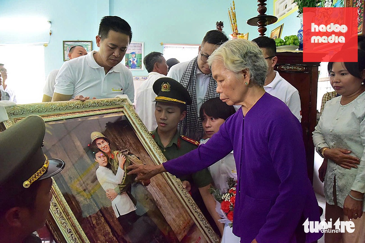 Bà Nguyễn Thị Lệ đưa tay chạm vào bức ảnh bà và liệt sĩ Huỳnh Văn Quên ôm nhau. Sau gần 6 thập kỷ chờ đợi, ông và bà đã được gần nhau hơn dù lời hứa hôn còn dang dở - Ảnh: TRÍ ĐỨC