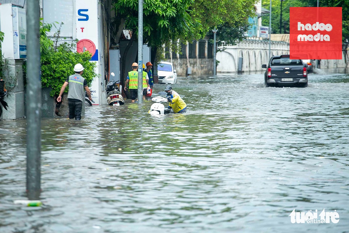 Xe bị chết máy, người dân bì bõm dắt bộ qua khu vực ngập sâu trên đường Thụy Khuê trưa 27-7 - Ảnh: C.TUỆ