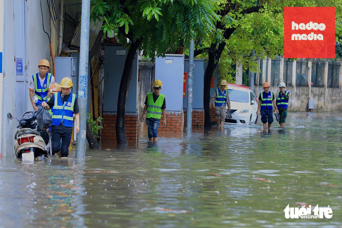 Công nhân ven theo vỉa hè sau giờ tan làm vì đường Thụy Khuê ngập sâu - Ảnh: DANH KHANG
