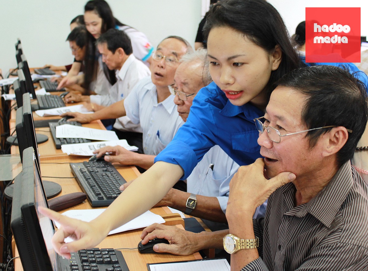 Tình nguyện viên hướng dẫn người cao tuổi sử dụng máy tính - Ảnh: TUỔI TRẺ