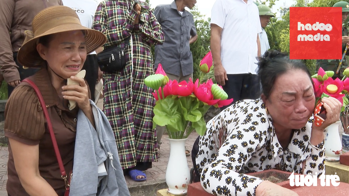 Người thân liệt sĩ Tình xúc động khi được cán bộ Đội quy tập thông báo tìm thấy mảnh nhôm và phiếu thông tin liệt sĩ trong phần mộ liệt sĩ chưa xác định được thông tin ở Nghĩa trang liệt sĩ Đô Lương, Nghệ An - Ảnh: HỒ VIỆT