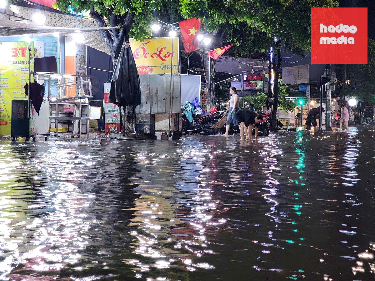 Điểm ngập ở ngã tư Lê Thánh Tôn - Phạm Văn Đồng, khi mưa giảm lưu lượng, người dân kiểm tra lại nắp ga bị che chắn - Ảnh: TRẦN MAI