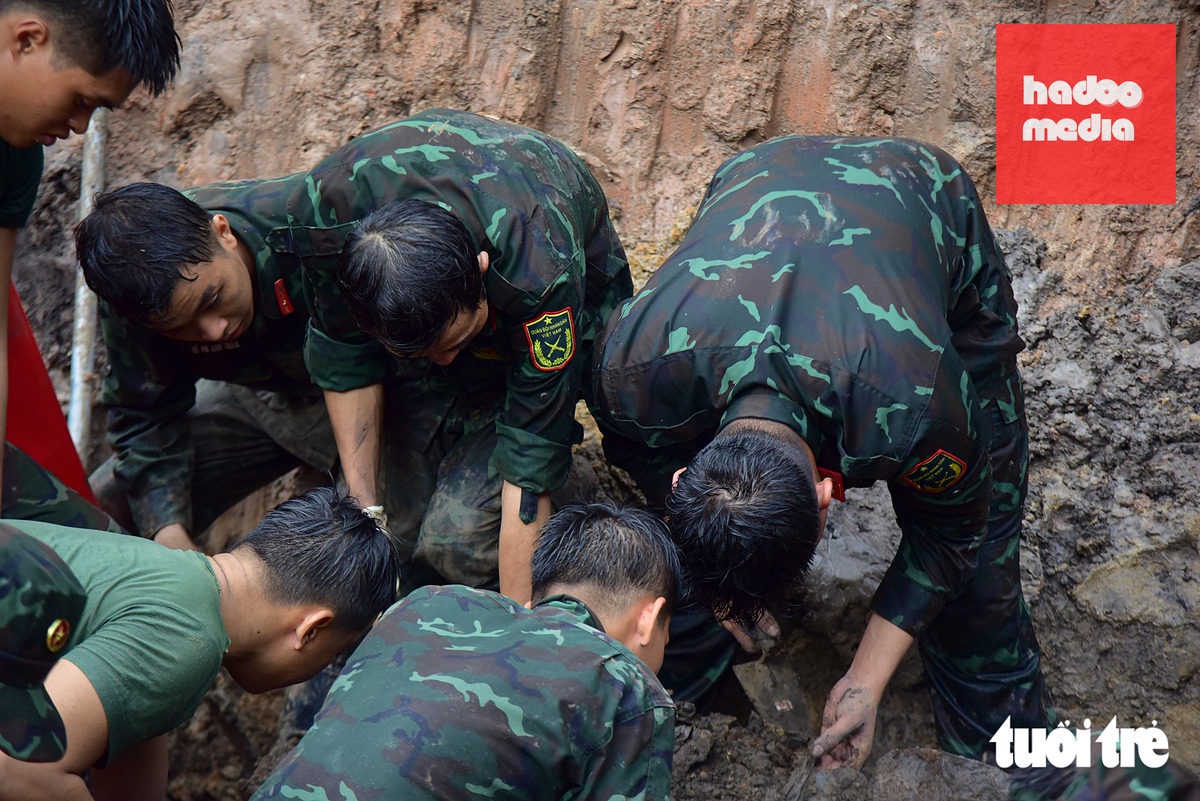 Những tấm lưng ướt đẫm mưa của các chiến sĩ Đội K74 vẫn bám hiện trường, kiên trì tìm kiếm hài cốt liệt sĩ tại công viên Lê Thị Riêng - Ảnh: TRÍ ĐỨC
