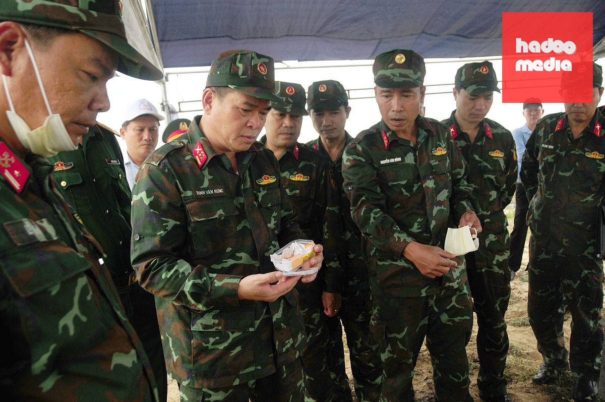 Đại tá Đinh Văn Hưng - Chính ủy Bộ Chỉ huy quân sự TP Đà Nẵng (thứ hai từ trái qua) kiểm tra di vật là chiếc nhẫn được tìm thấy dưới mộ liệt sĩ - Ảnh: B.D.