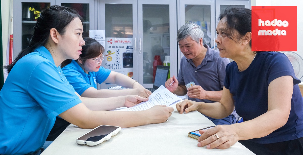 Cán bộ bảo hiểm xã hội hỗ trợ người dân kê khai thông tin ủy quyền hưởng lương hưu tại Hà Nội - Ảnh: HÀ QUÂN