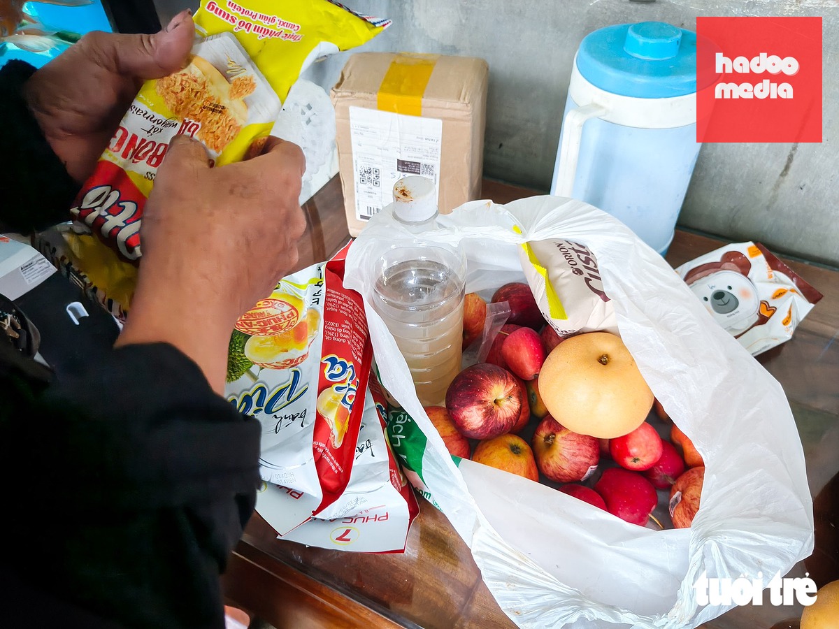 Người nhà mở túi quà là bánh kẹo, trái cây mà bà K. mua về cho cháu trên chuyến xe định mệnh - Ảnh: TẤN LỰC