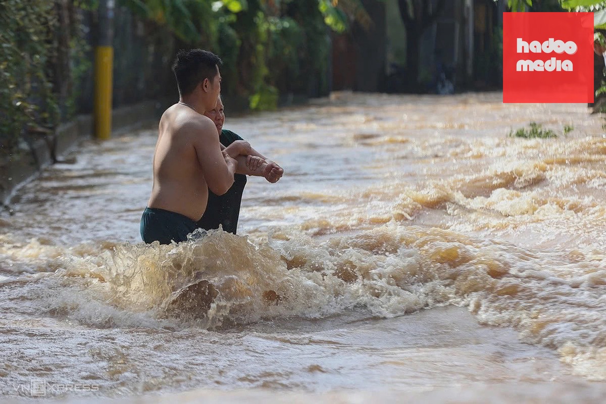 Người dân Phước Tân dìu nhau qua đoạn nước chảy siết ở khu dân cư sáng 12/9. Ảnh: Phước Tuấn