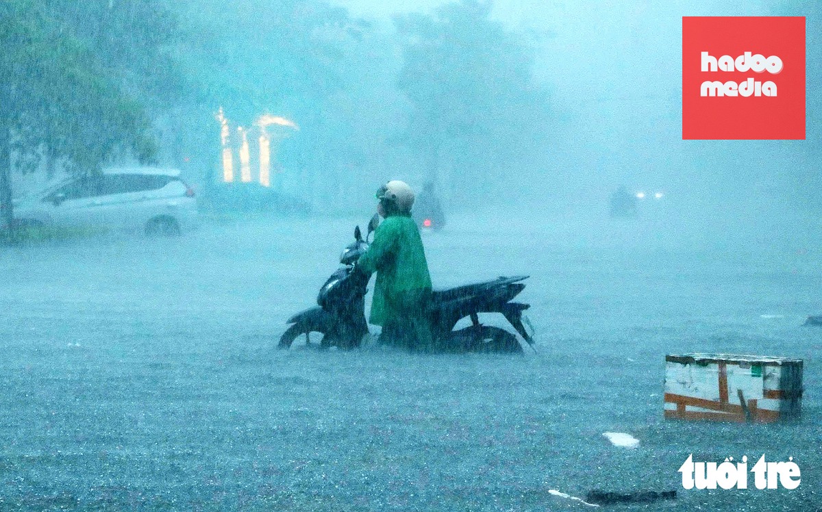 Người dân dắt xe máy trong cơn mưa tầm tã, đường ngập trên đoạn đường An Dương Vương, phường Trường Vinh, Nghệ An - Ảnh: DOÃN HÒA