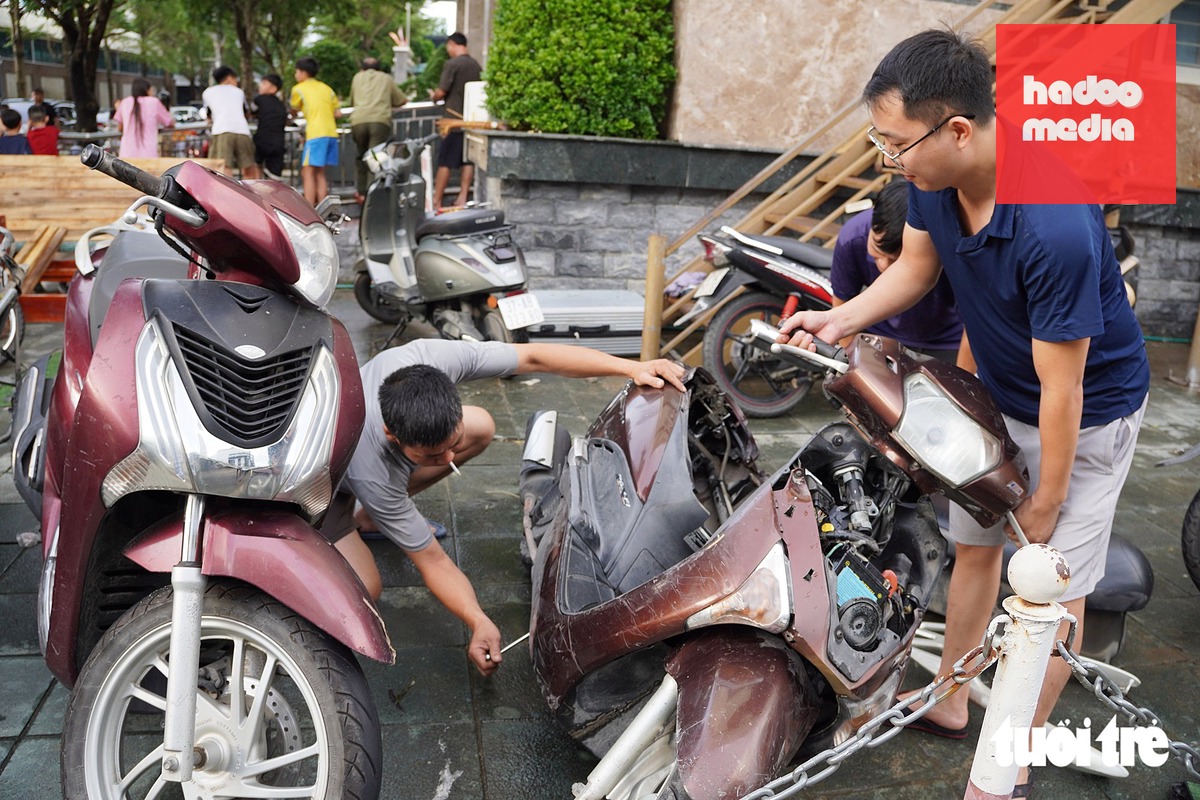 Thợ sửa xe sau đó có mặt tại khu vực chung cư để hỗ trợ cư dân xử lý những chiếc xe bị ngập. Các phương tiện được kiểm tra, tháo nước và làm sạch những bộ phận có nguy cơ bị ảnh hưởng do ngâm nước - Ảnh: DOÃN HÒA
