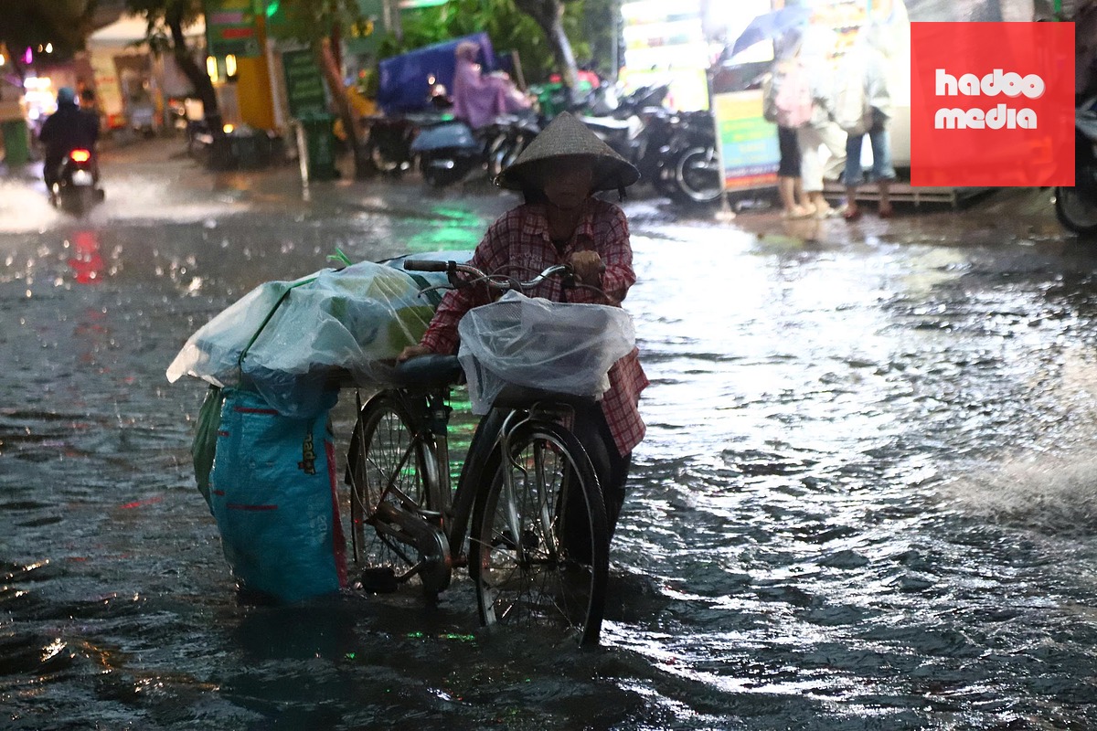 Người lao động di chuyển khó khăn qua khu vực nước ngập trong cơn mưa chiều 22-9 - Ảnh: NGỌC LÂN