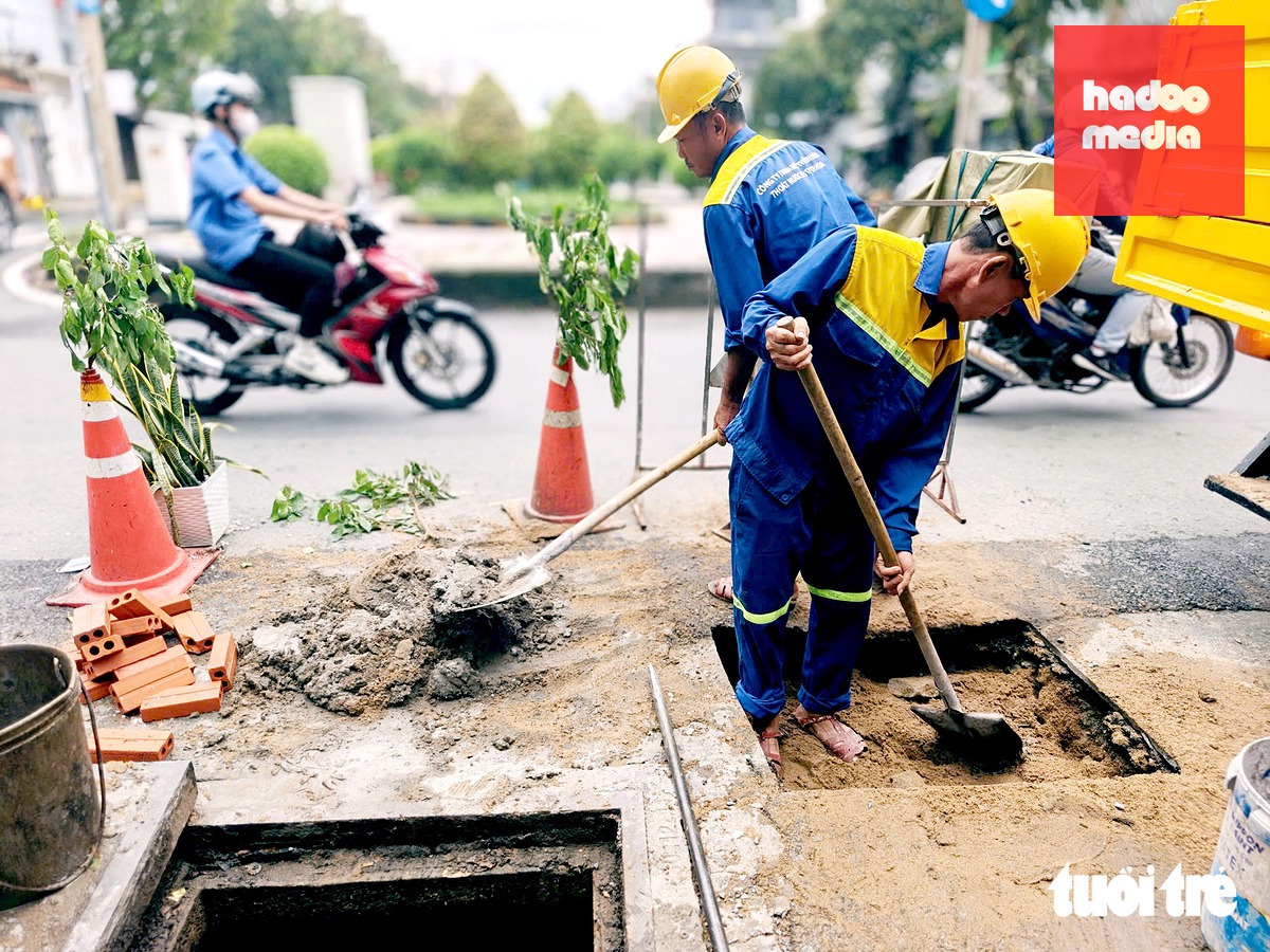 Công nhân Công ty TNHH MTV Thoát nước đô thị TP.HCM có mặt khắc phục sự cố hố sụt lún tại khu vực đường Văn Cao - Hiền Vương sáng 23-9 - Ảnh: TRÍ ĐỨC