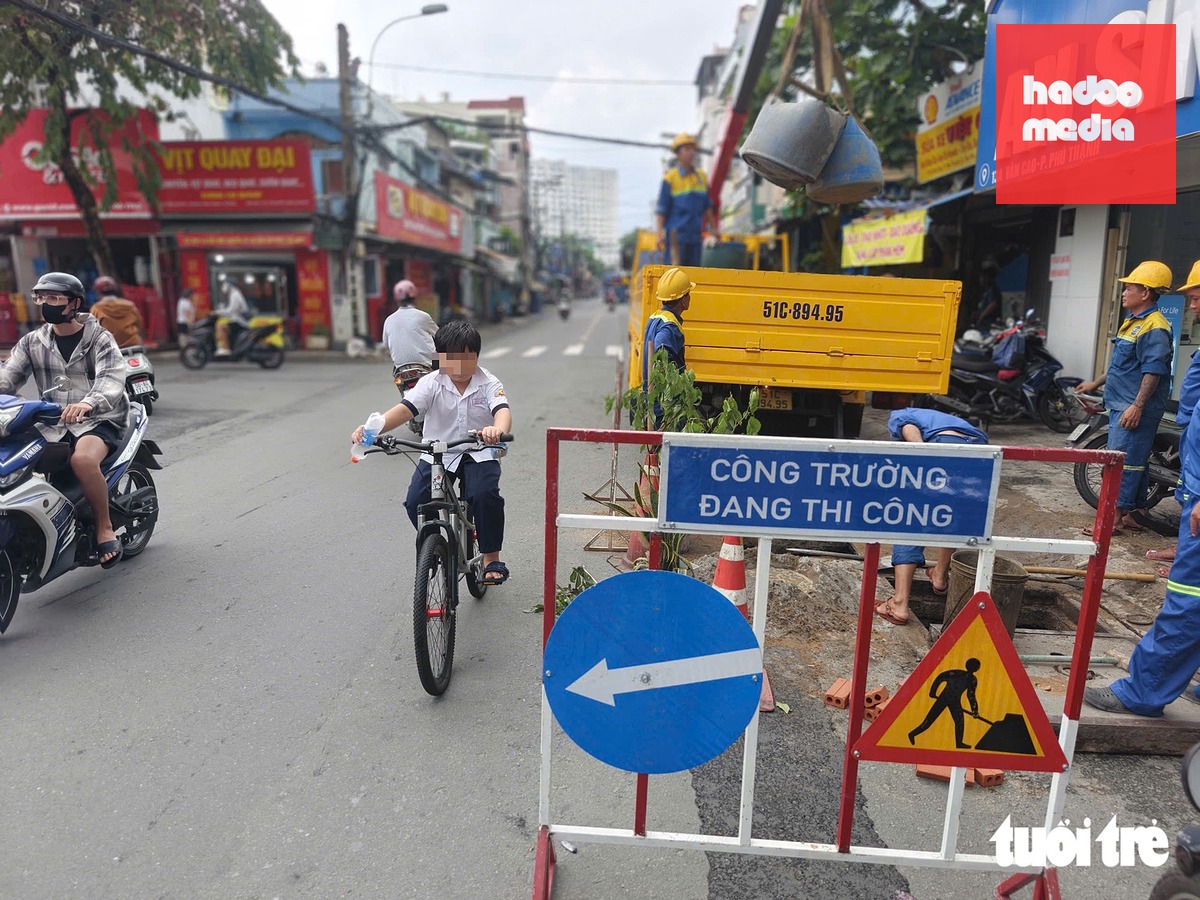 Công nhân đặt rào chắn để khắc phục sự cố, khu vực hố sụt lún này thường xuyên có học sinh qua lại - Ảnh: TRÍ ĐỨC