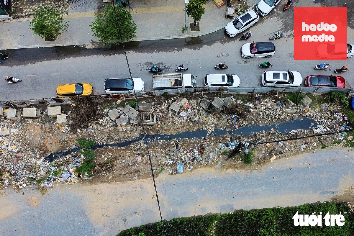 Sau khoảng 10 năm, đến nay tuyến đường vẫn đang dang dở, chưa thi công xong. Bên trong khu vực thi công bị đổ trộm rác thải, còn phía bên ngoài ô tô đỗ bừa bãi - Ảnh: PHÚC TÀI