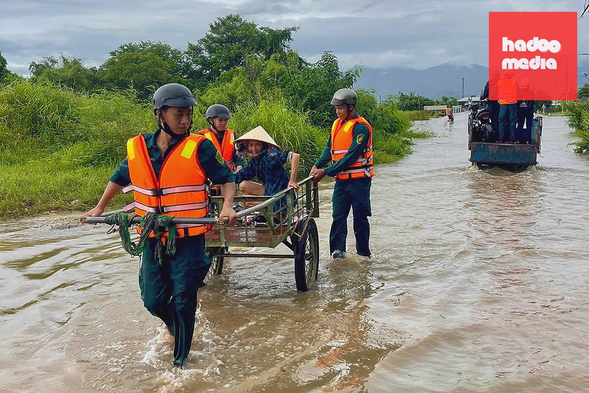 Lực lượng dân quân hỗ trợ người dân di chuyển qua khu vực ngập nước. Ảnh: Tư Huynh