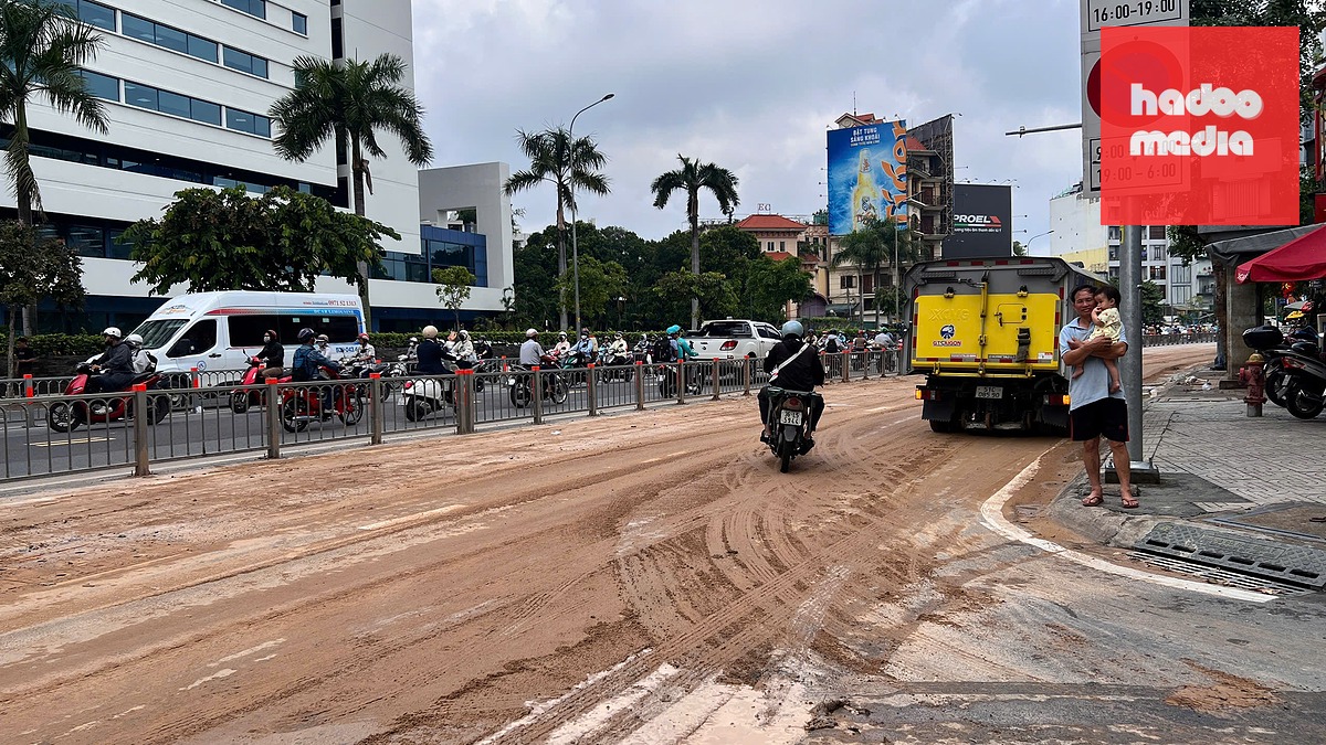 Đất rơi xuống đường gặp mưa nên nhão nhoẹt, làm người đi xe máy té ngã - Ảnh: MINH TUẤN