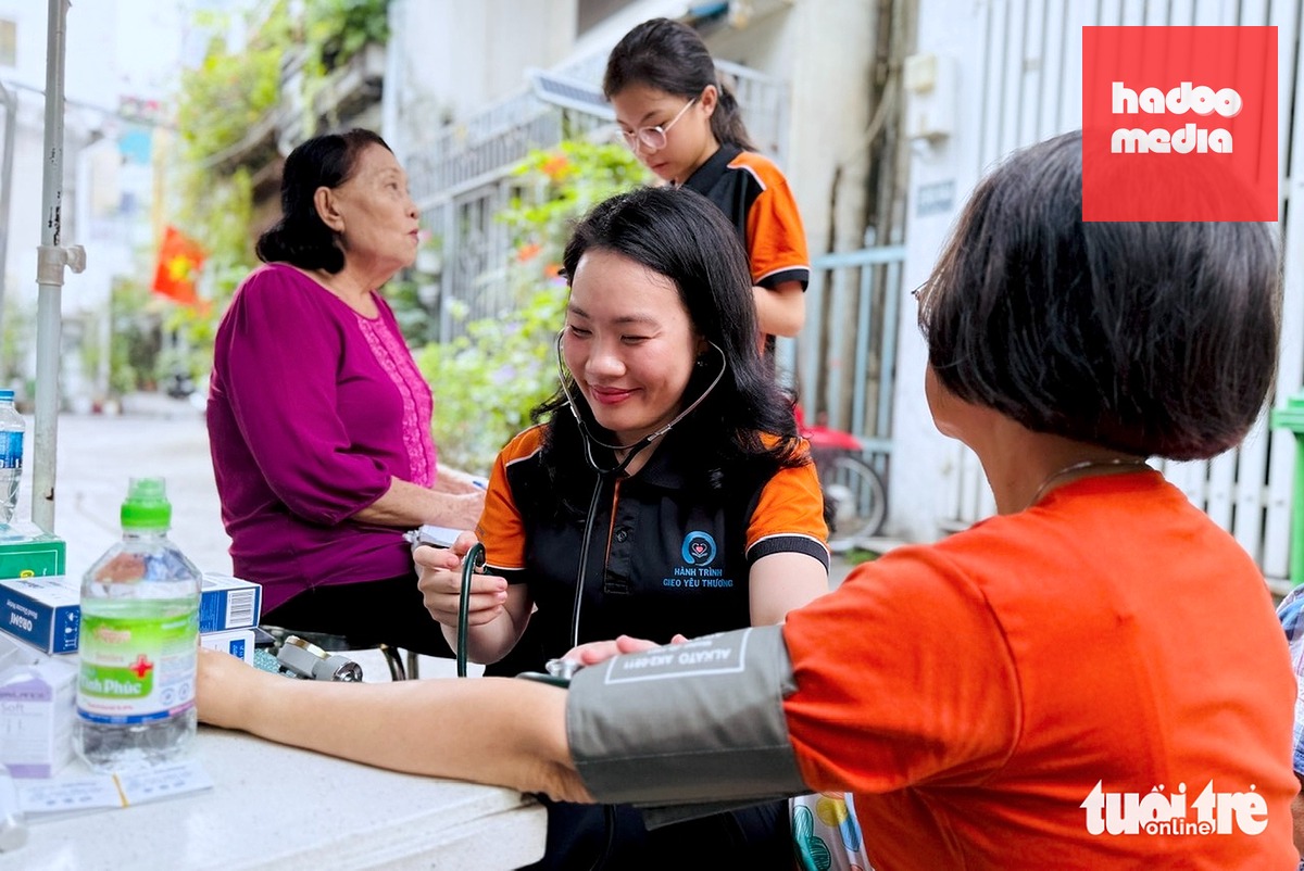 Tiến sĩ Nguyễn Thị Hải Liên - giảng viên khoa y tế công cộng, Trường đại học Y Dược TP.HCM - hỗ trợ đo huyết áp cho người dân và tham gia tư vấn cho những người có nhu cầu được theo dõi sức khỏe mỗi ngày tại phường Xuân Hòa - Ảnh: LÊ PHAN