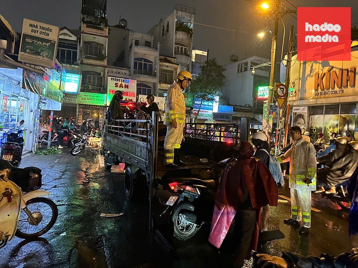 Cảnh sát giao thông dùng xe nâng hỗ trợ đưa xe chết máy qua điểm ngập - Ảnh: PC08