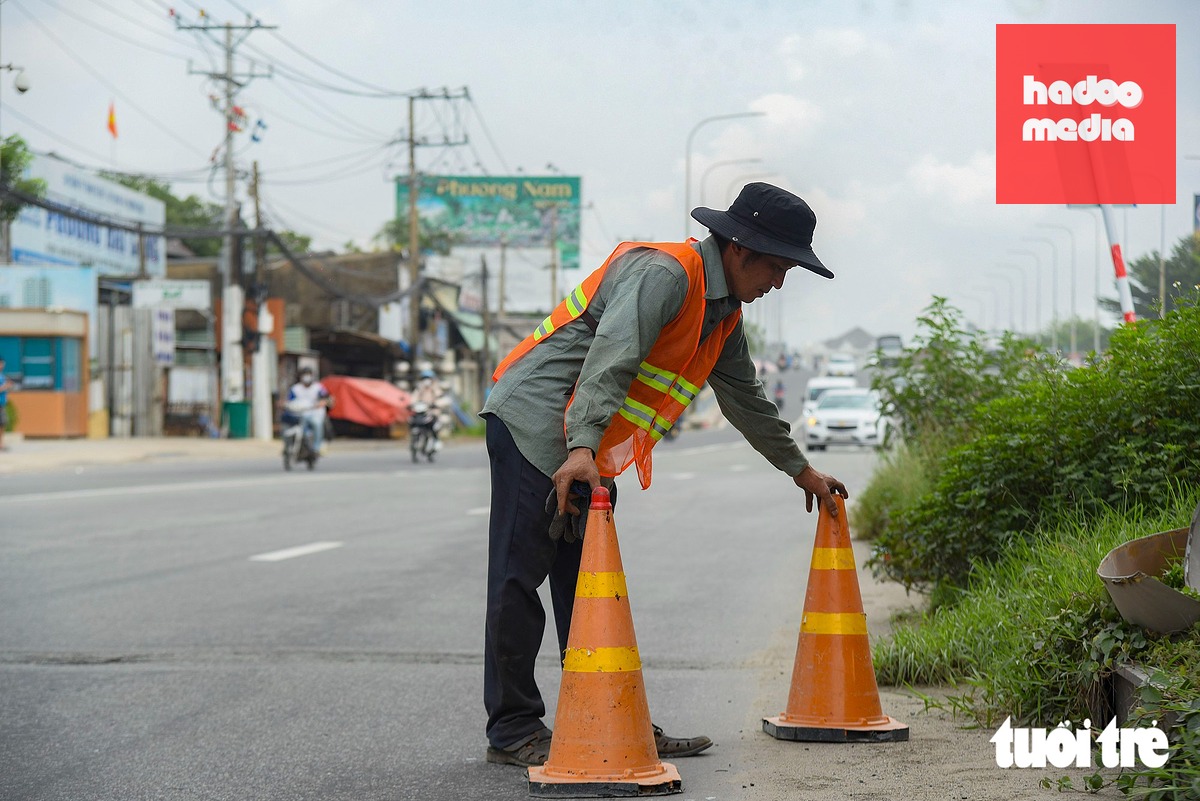 Công nhân dựng trụ cảnh báo cọc tiêu giao thông khi tháo dỡ cổng chào Bình Dương cũ - Ảnh: TRÍ ĐỨC