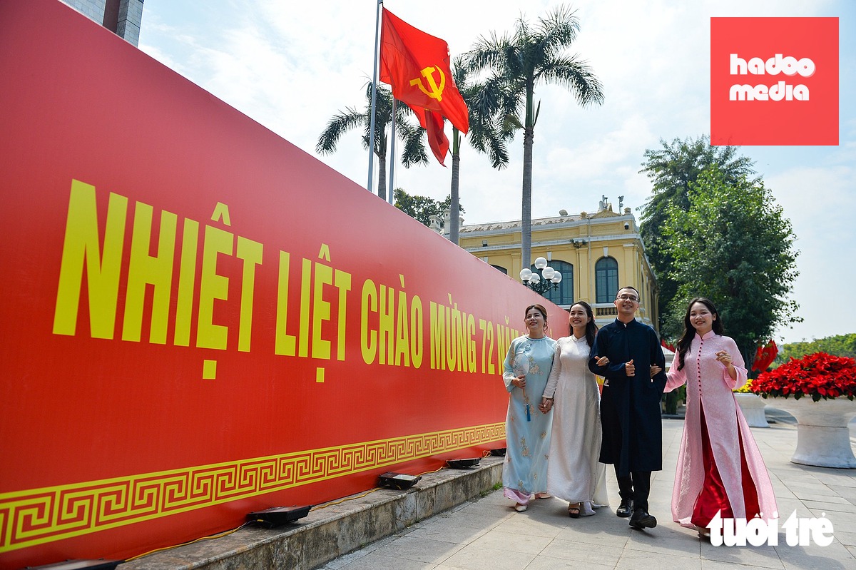 Chị Trần Phương Thảo (phường Thanh Xuân, Hà Nội - thứ hai từ trái qua) cùng các bạn chụp ảnh trước dòng chữ chào mừng 72 năm Ngày Giải phóng Thủ đô đặt trước UBND thành phố Hà Nội - Ảnh: PHÚC TÀI