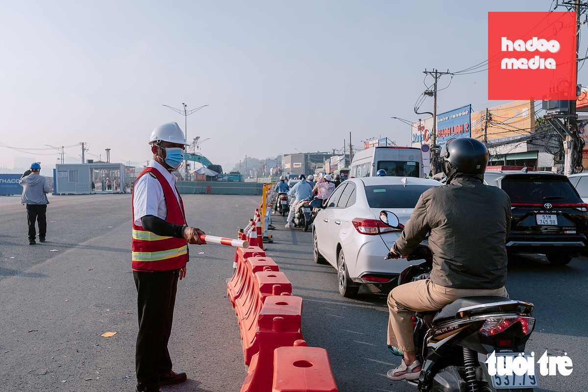 Nhân viên tại khu vực thi công hỗ trợ điều tiết phương tiện qua khu vực rào chắn - Ảnh: HỮU DUY