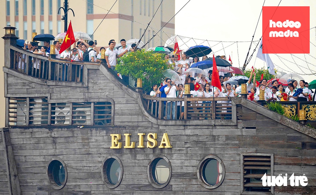 Đông nghịt người dân thành phố, nhân viên Nutifoof... đứng kín trên tàu nhà hàng Elisa đón đoàn lai dắt nhịp cầu đi bộ về đích - Ảnh: THUẬN VĂN