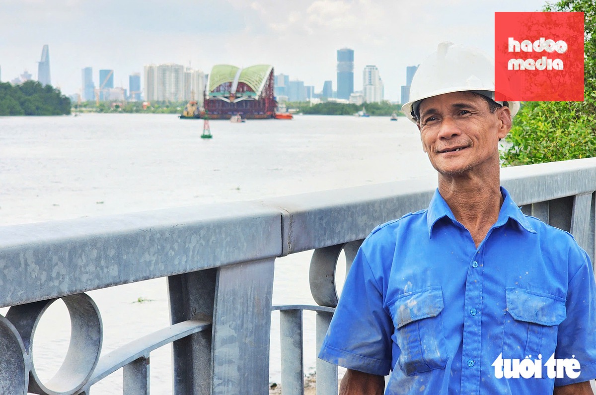 Ông Lê Văn Vân chụp ảnh cùng với nhịp cầu đi bộ đang lai dắt trên sông Sài Gòn khi qua khu vực quận 2 cũ - Ảnh: NGỌC KHẢI
