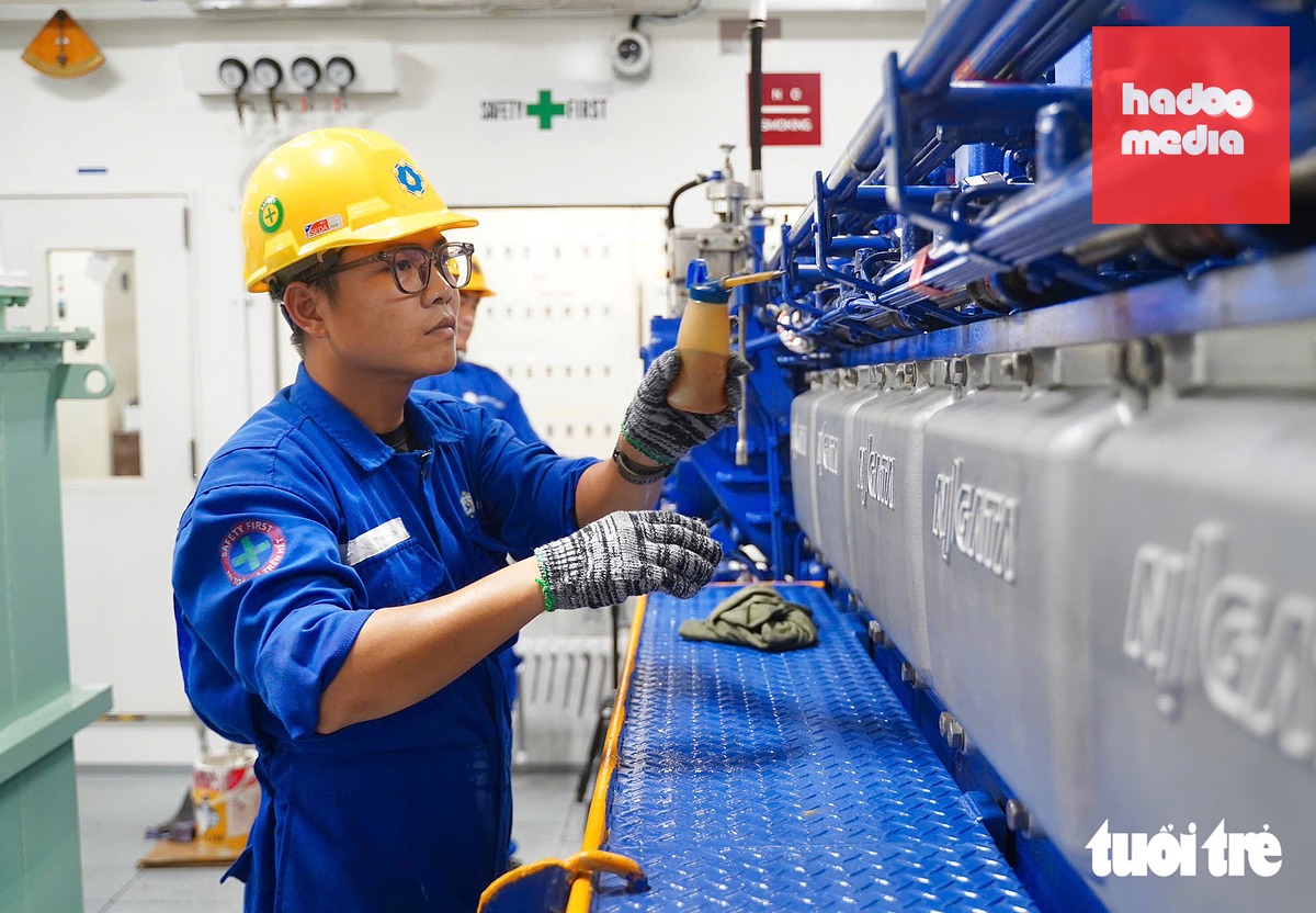 Cùng lúc, thợ máy Phạm Tuấn Kiệt tra dầu nhớt vào trang thiết bị của máy chính trong buồng máy, đảm bảo thiết thiết bị vận hành đạt hiệu quả cao nhất - Ảnh: THUẬN VĂN