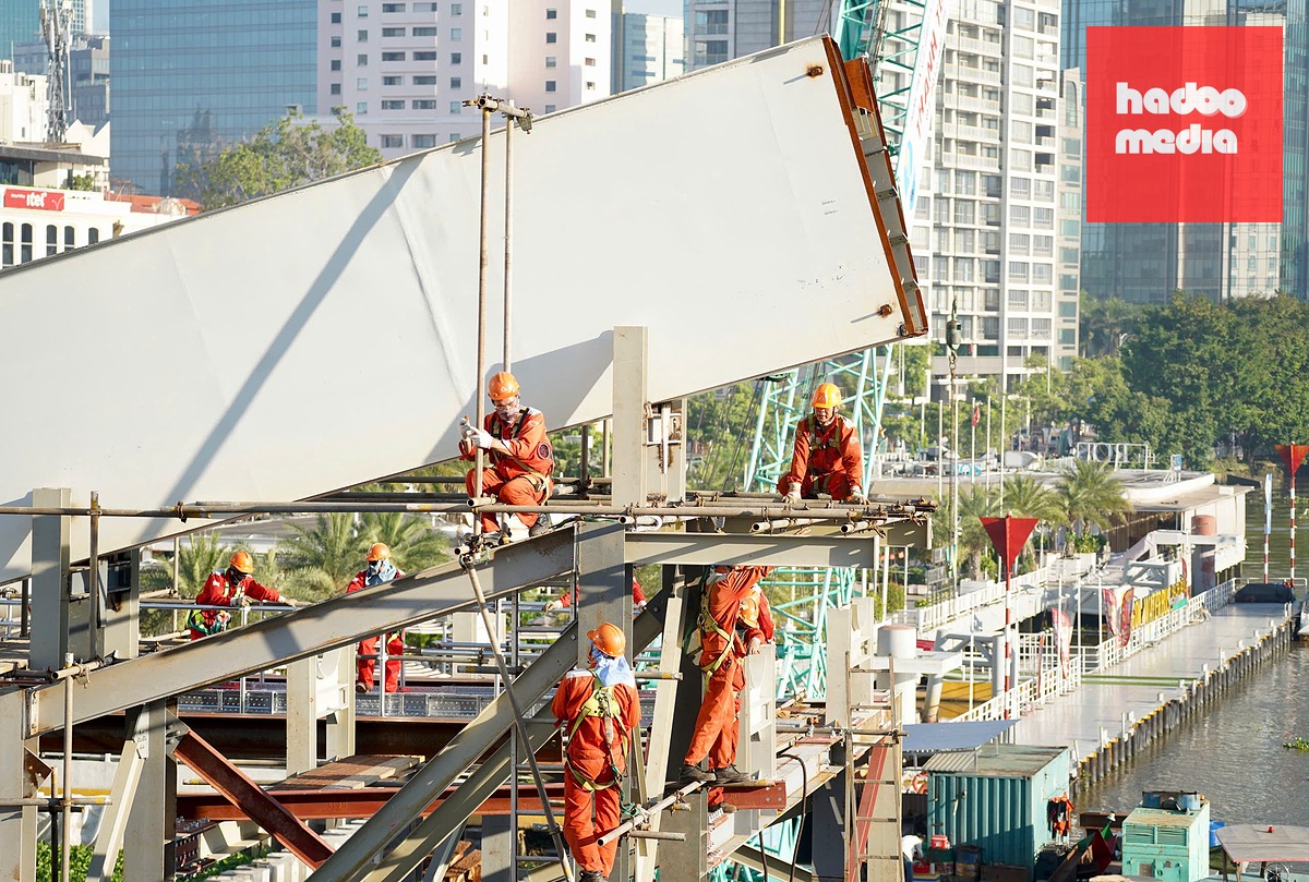 Lúc 7h5, khu vực mố cầu kết nối nhịp dẫn với nhịp chính cầu đi bộ phía bến Bạch Đằng, không khí làm việc khẩn trương của đội ngũ công nhân, kỹ sư - Ảnh: THUẬN VĂN