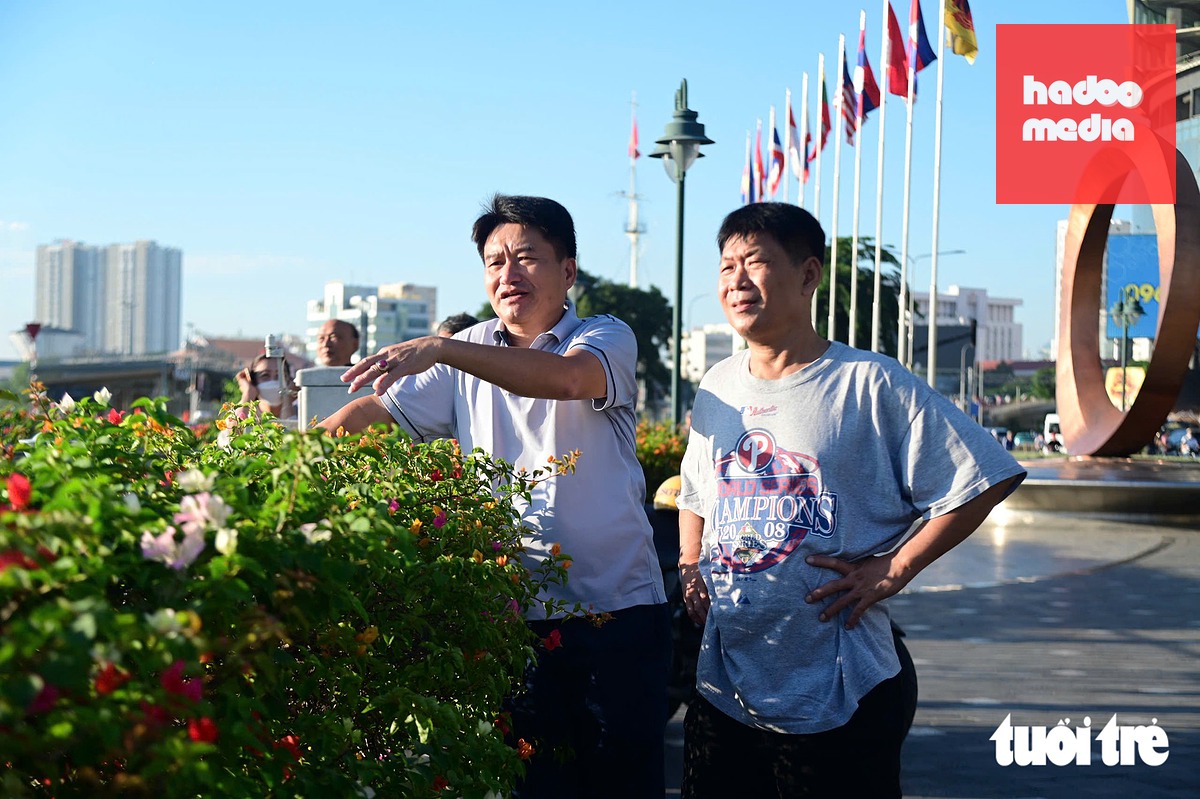 Ông Nguyễn Văn Hiệu (du khách) cùng bạn đứng từ xa theo dõi quá trình hợp long cầu đi bộ và cho biết diện mạo khu vực sẽ thêm khang trang, góp phần nối liền đôi bờ sông Sài Gòn - Ảnh: TRÍ ĐỨC