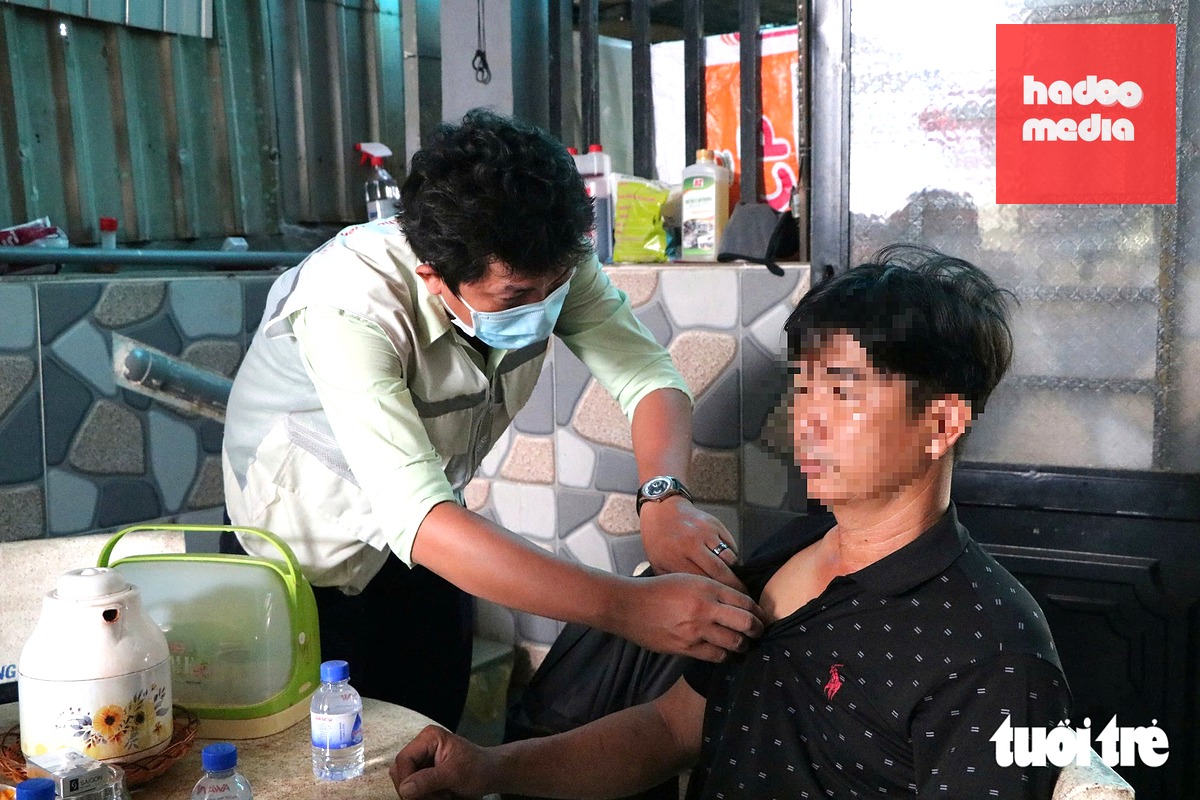 Nhân viên y tế nhẹ nhàng kiểm tra thân nhiệt, hỏi thăm tình trạng sức khỏe của từng người trong gia đình có ca bệnh tử vong do não mô cầu - Ảnh: THU HIẾN