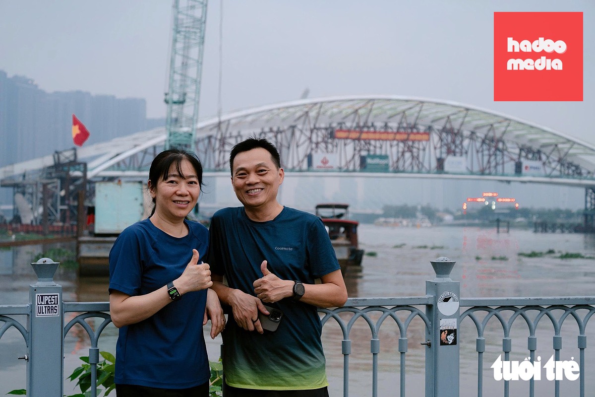 Anh Ngọc Thuấn cùng vợ tập thể dục sáng tranh thủ lưu lại những bức hình cùng cầu đi bộ qua sông Sài Gòn đang dần hình thành - Ảnh: HỮU DUY