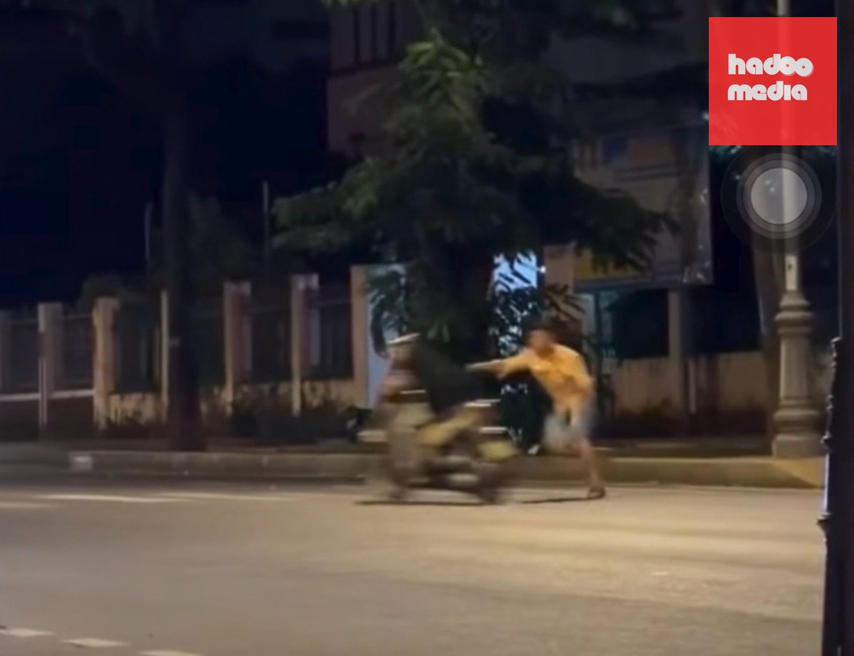 Người đàn ông áo vàng cầm dây nịt đánh người đi đường - Ảnh: Cắt từ clip