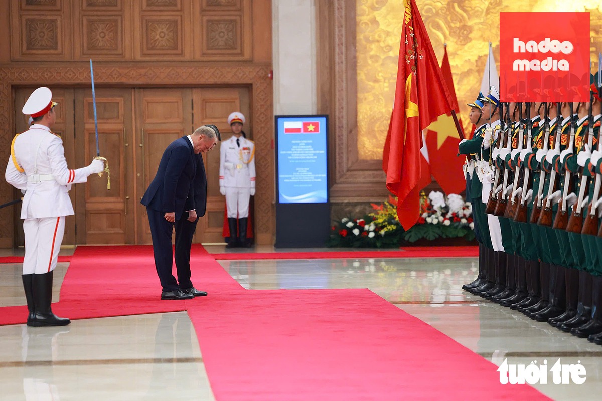 Thủ tướng Lê Minh Hưng và Thủ tướng Ba Lan Donald Tusk cúi chào quân kỳ Quân đội nhân dân Việt Nam - Ảnh: NGUYỄN KHÁNH